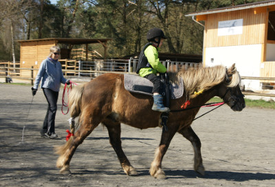 Fálki mit einem Kind auf dem Reitplatz